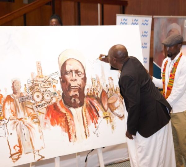 Owek. Mugenyi Fred Rucunya, the Chief Prince of Bunyoro-Kitara Kingdom signing 100 Years of Kabalega commemoration  artwork by Mr. Tibirushya.